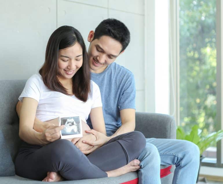 Pasangan suami istri berpose dengan usg